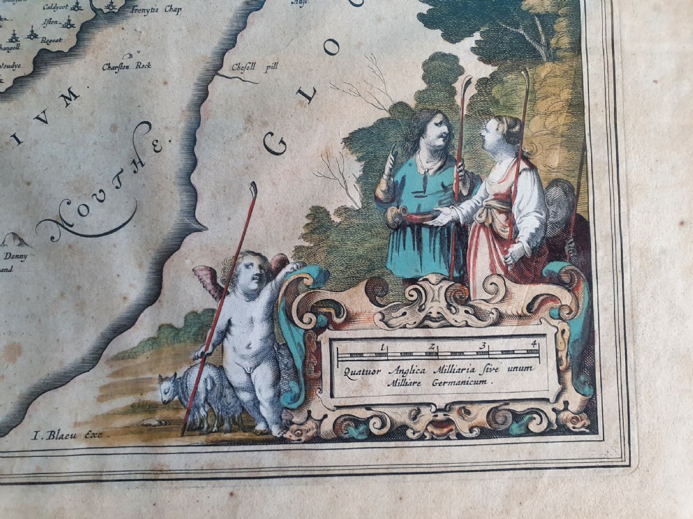 A framed 17th-century hand-coloured map of Monmouthshire featuring coats of arms, figures, a decorative cartouche, and a gilded wood frame. View VI