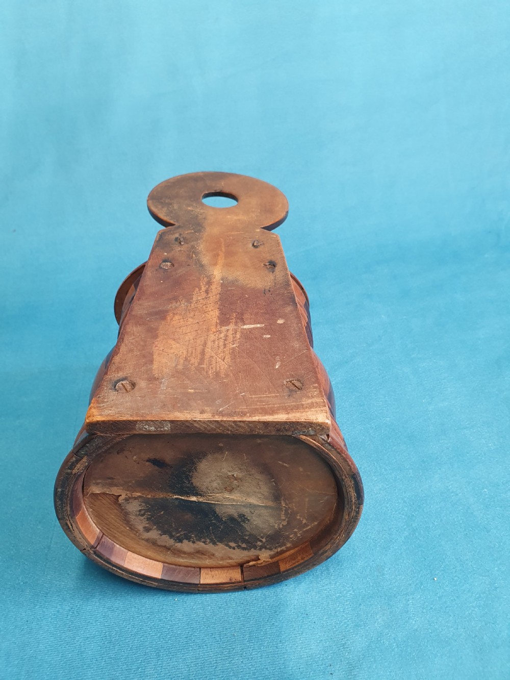 A mid-19th-century turned wooden wall-hanging salt box with staved multi-tone timber construction, a circular hinged lid, and a pierced round backboard. View VI