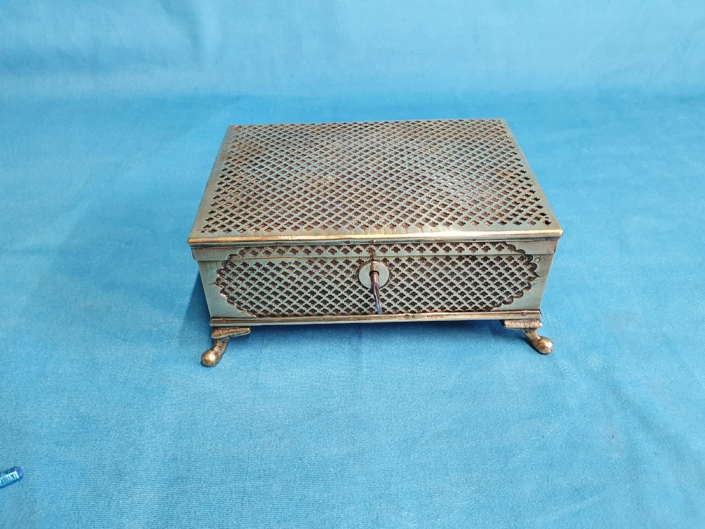 A late nineteenth-century rectangular brass jewellery box featuring pierced lattice fretwork, small corner feet, and a front keyhole.