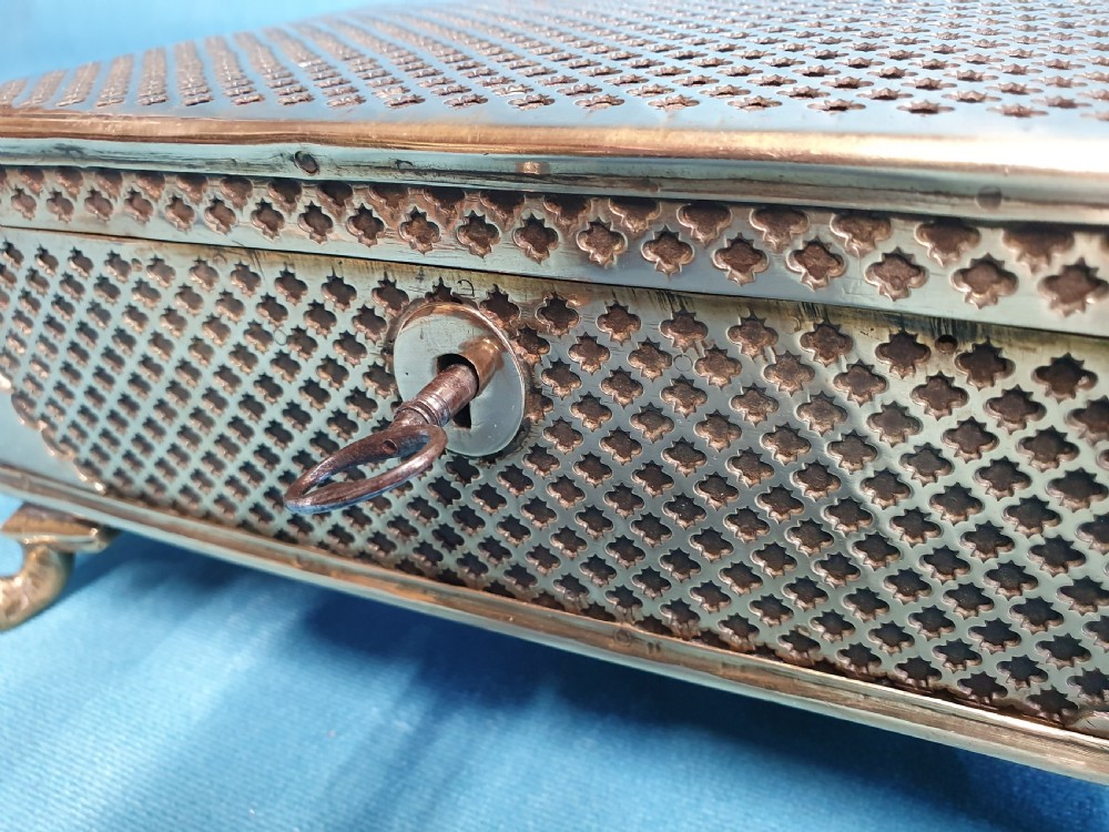 A late nineteenth-century rectangular brass jewellery box featuring pierced lattice fretwork, small corner feet, and a front keyhole. View III