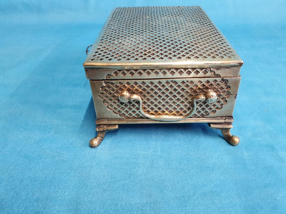 A late nineteenth-century rectangular brass jewellery box featuring pierced lattice fretwork, small corner feet, and a front keyhole. View IX