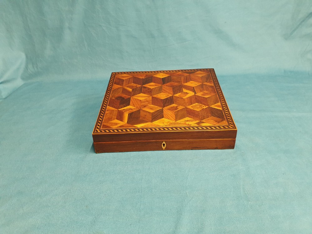 A 19th-century rectangular wooden writing slope featuring geometric tumbling block parquetry inlay and a brass keyhole escutcheon.