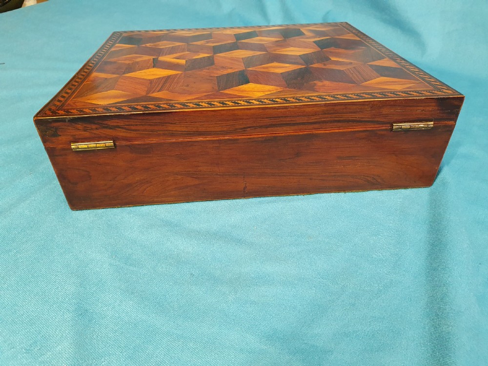 A 19th-century rectangular wooden writing slope featuring geometric tumbling block parquetry inlay and a brass keyhole escutcheon. View III