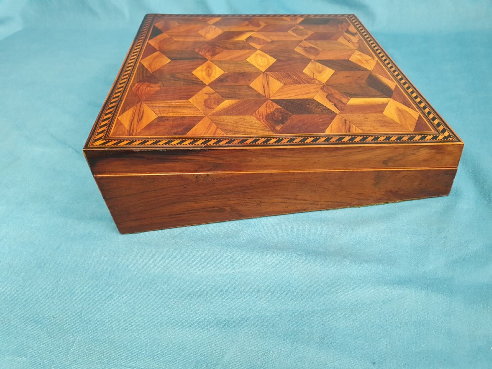 A 19th-century rectangular wooden writing slope featuring geometric tumbling block parquetry inlay and a brass keyhole escutcheon. View V
