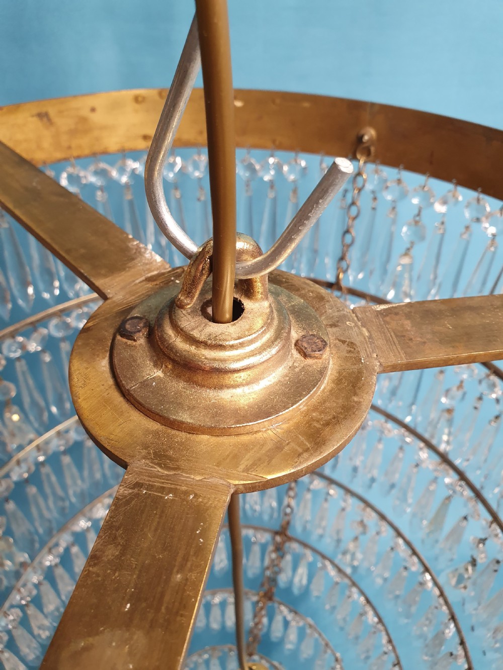 A seven-tiered waterfall chandelier featuring concentric brass rings strung with elongated clear crystal spikes, ending in a single spherical glass finial. View VII