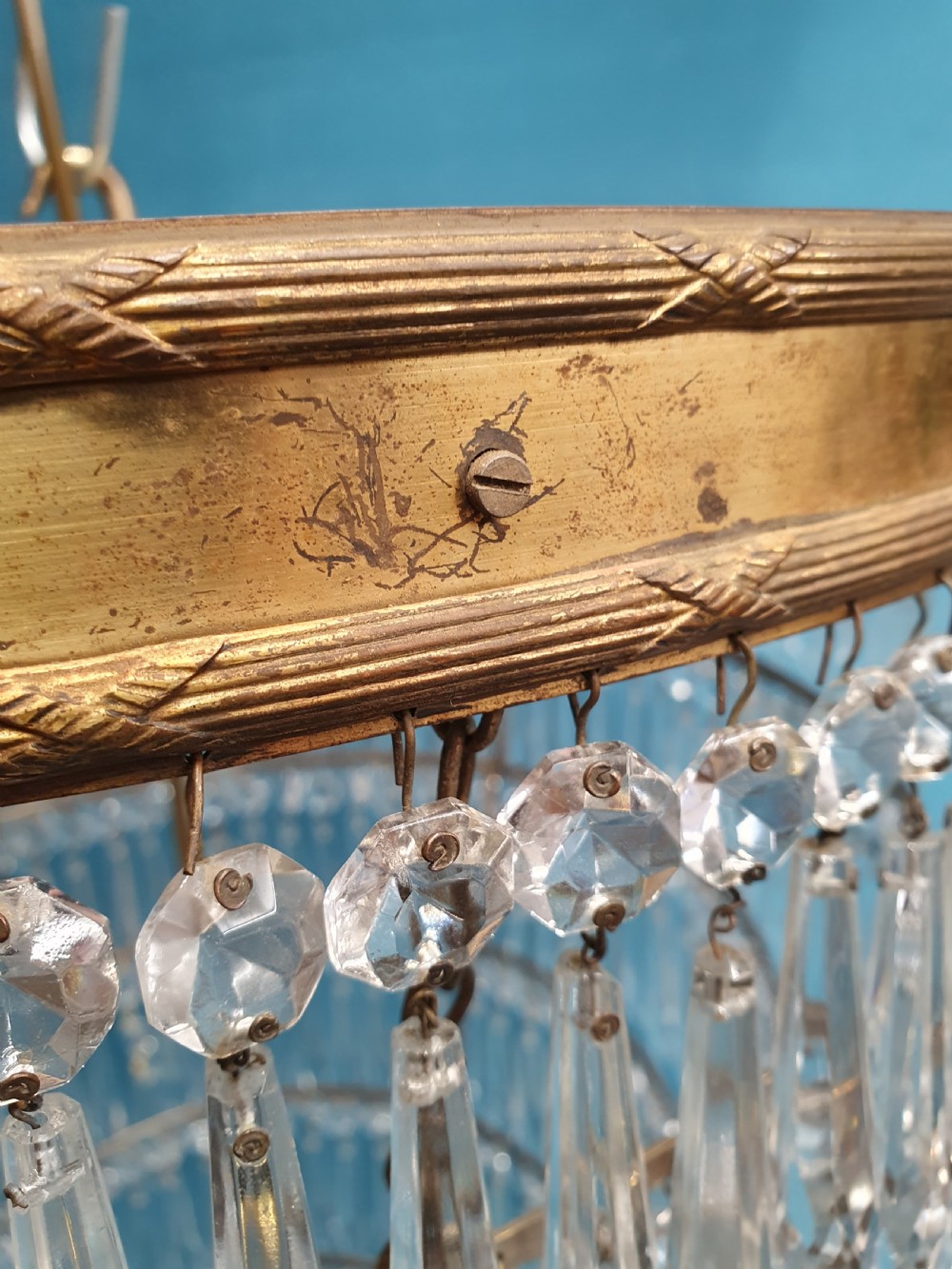 A seven-tiered waterfall chandelier featuring concentric brass rings strung with elongated clear crystal spikes, ending in a single spherical glass finial. View IX