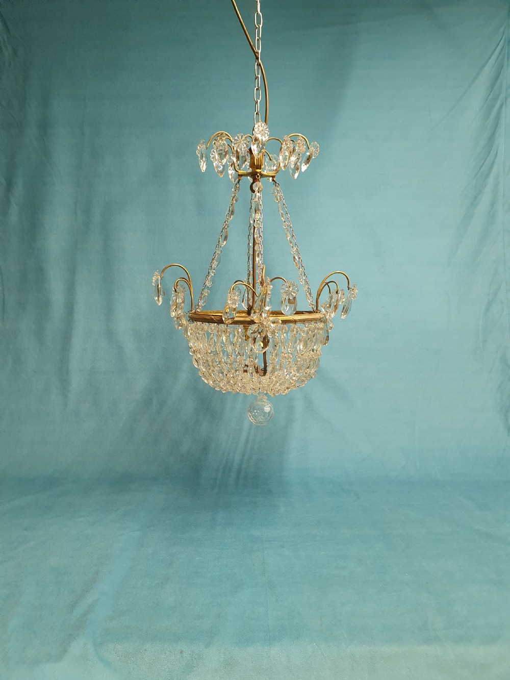 An early 20th-century ceiling chandelier featuring a brass frame hung with cascading cut glass beads forming a basket shape, crowned with scrolled arms holding glass droplets.