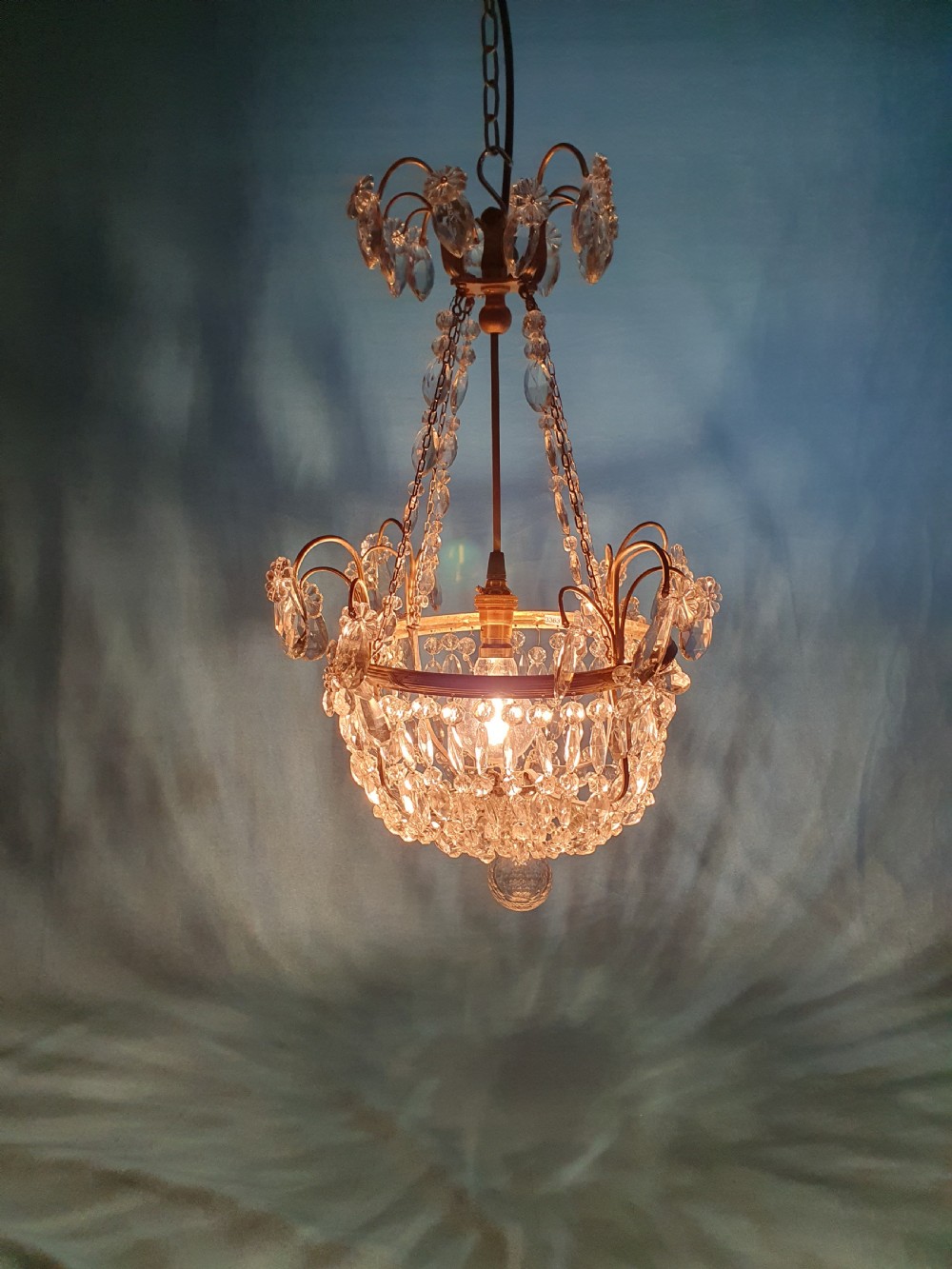 An early 20th-century ceiling chandelier featuring a brass frame hung with cascading cut glass beads forming a basket shape, crowned with scrolled arms holding glass droplets. View II