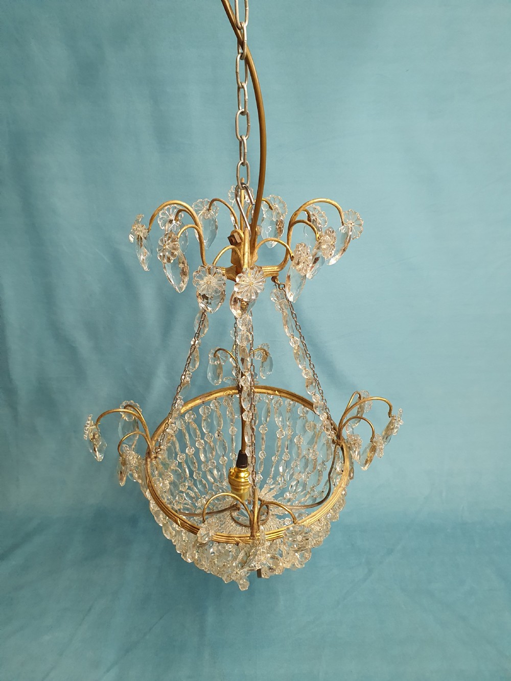 An early 20th-century ceiling chandelier featuring a brass frame hung with cascading cut glass beads forming a basket shape, crowned with scrolled arms holding glass droplets. View V
