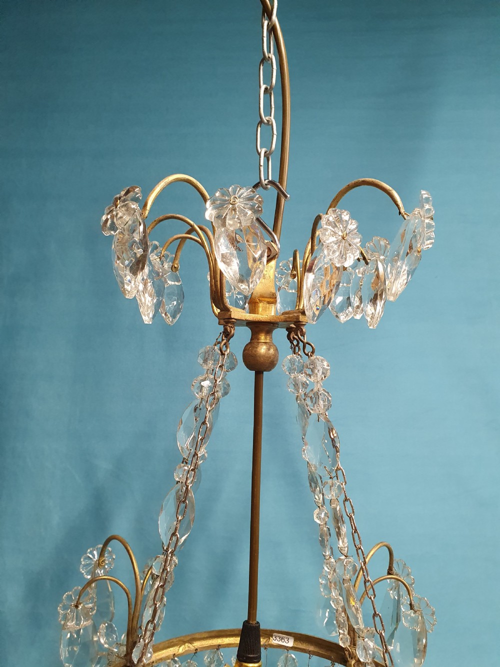 An early 20th-century ceiling chandelier featuring a brass frame hung with cascading cut glass beads forming a basket shape, crowned with scrolled arms holding glass droplets. View VI