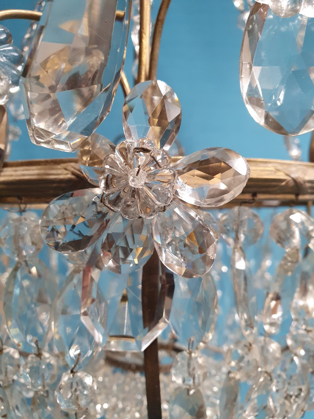 An early 20th-century ceiling chandelier featuring a brass frame hung with cascading cut glass beads forming a basket shape, crowned with scrolled arms holding glass droplets. View VIII