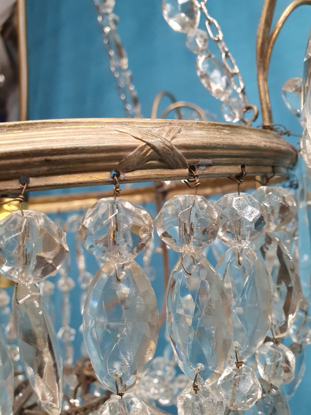 An early 20th-century ceiling chandelier featuring a brass frame hung with cascading cut glass beads forming a basket shape, crowned with scrolled arms holding glass droplets. View IX