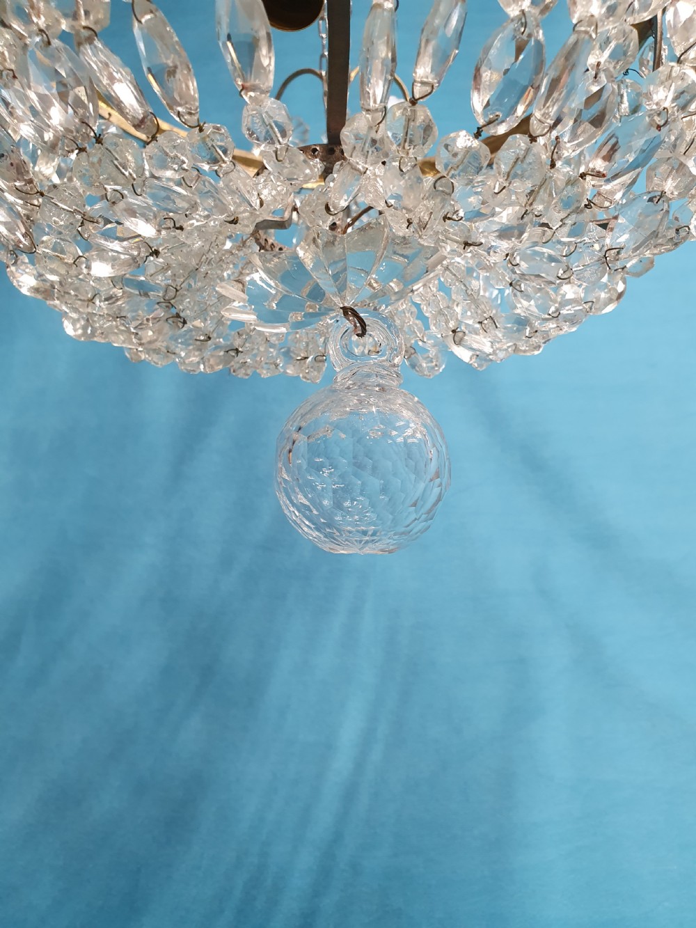 An early 20th-century ceiling chandelier featuring a brass frame hung with cascading cut glass beads forming a basket shape, crowned with scrolled arms holding glass droplets. View X