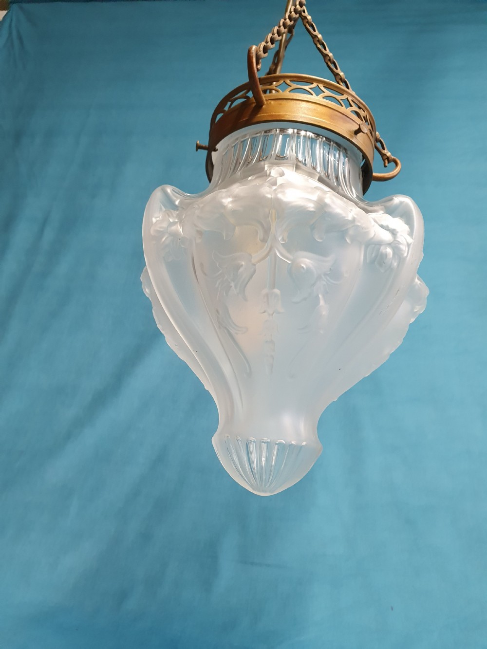 An early 20th-century glass pendant light with a frosted and moulded glass shade suspended by brass chains from a decorative brass gallery. View II