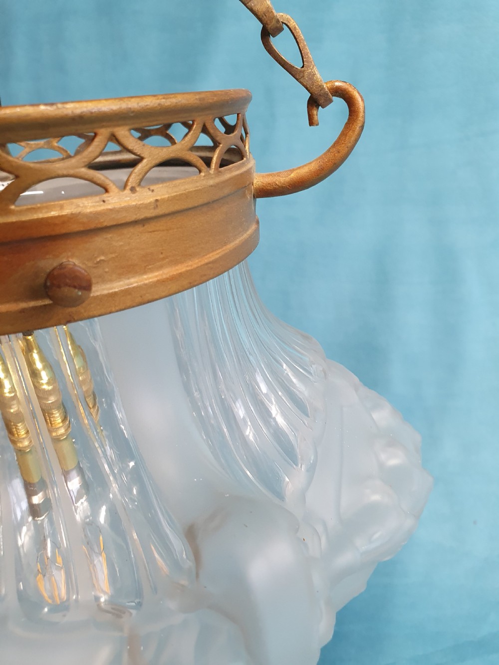 An early 20th-century glass pendant light with a frosted and moulded glass shade suspended by brass chains from a decorative brass gallery. View V