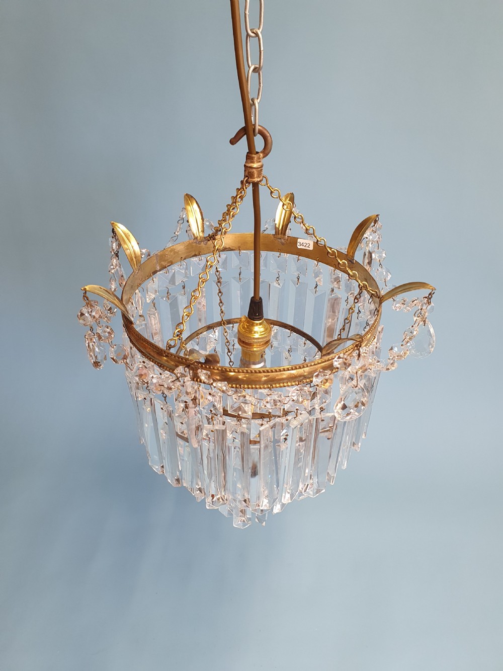 An early 20th-century tiered brass chandelier featuring rows of clear oblong crystal prisms suspended from a circular metal frame. View VIII