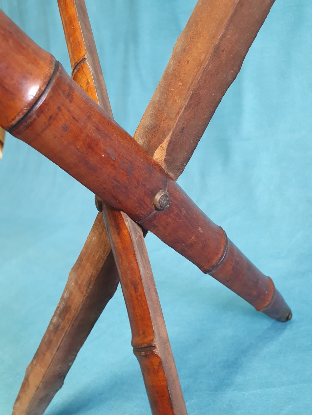 An antique cherry wood folding rod rest featuring carved faux bamboo turnings and a crossed X-frame structure. View III