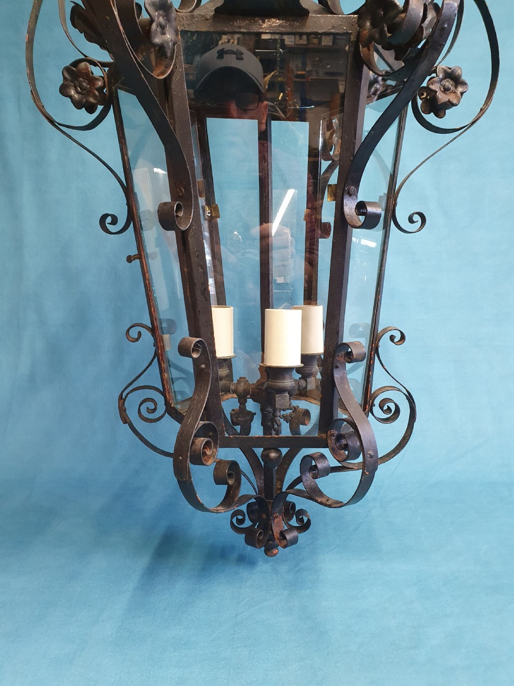 An early 20th-century wrought steel hanging porch lantern featuring elaborate scrollwork, leaf accents, clear glass panels, and an internal multi-bulb light fitting. View VI