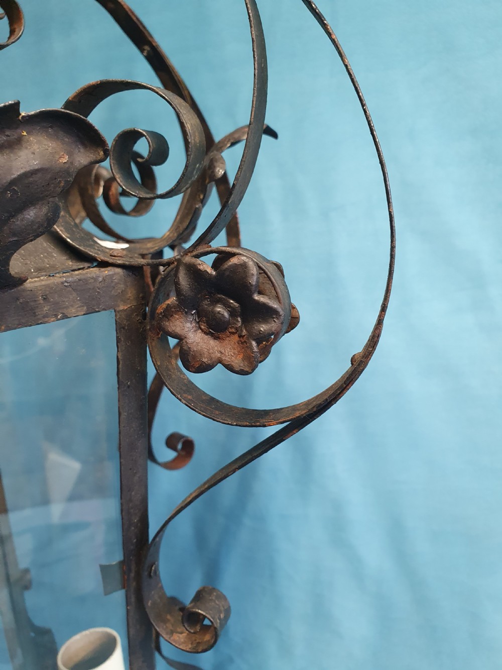 An early 20th-century wrought steel hanging porch lantern featuring elaborate scrollwork, leaf accents, clear glass panels, and an internal multi-bulb light fitting. View VIII