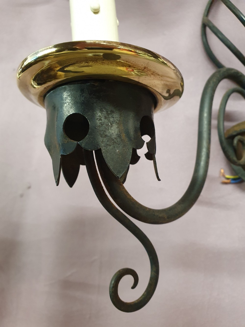 A trio of early twentieth-century dark steel twin-arm wall sconces featuring openwork twisted central cages, scrolled arms, and polished brass accents. View III