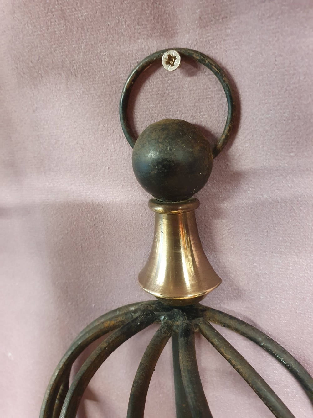 A trio of early twentieth-century dark steel twin-arm wall sconces featuring openwork twisted central cages, scrolled arms, and polished brass accents. View V