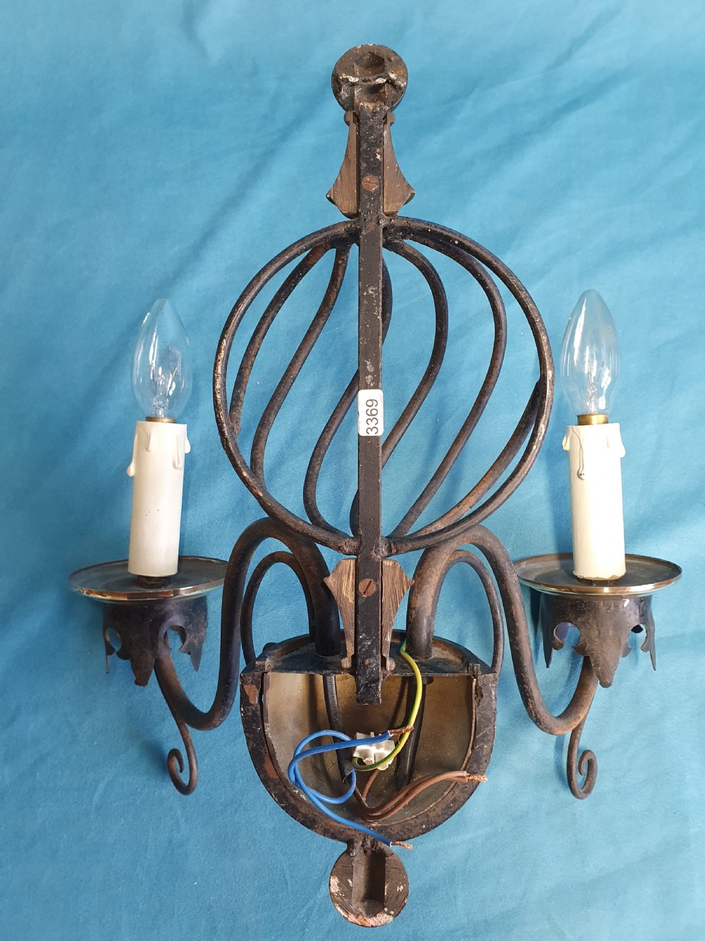 A trio of early twentieth-century dark steel twin-arm wall sconces featuring openwork twisted central cages, scrolled arms, and polished brass accents. View VII