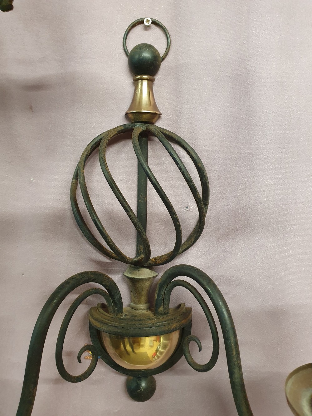 A trio of early twentieth-century dark steel twin-arm wall sconces featuring openwork twisted central cages, scrolled arms, and polished brass accents. View VIII