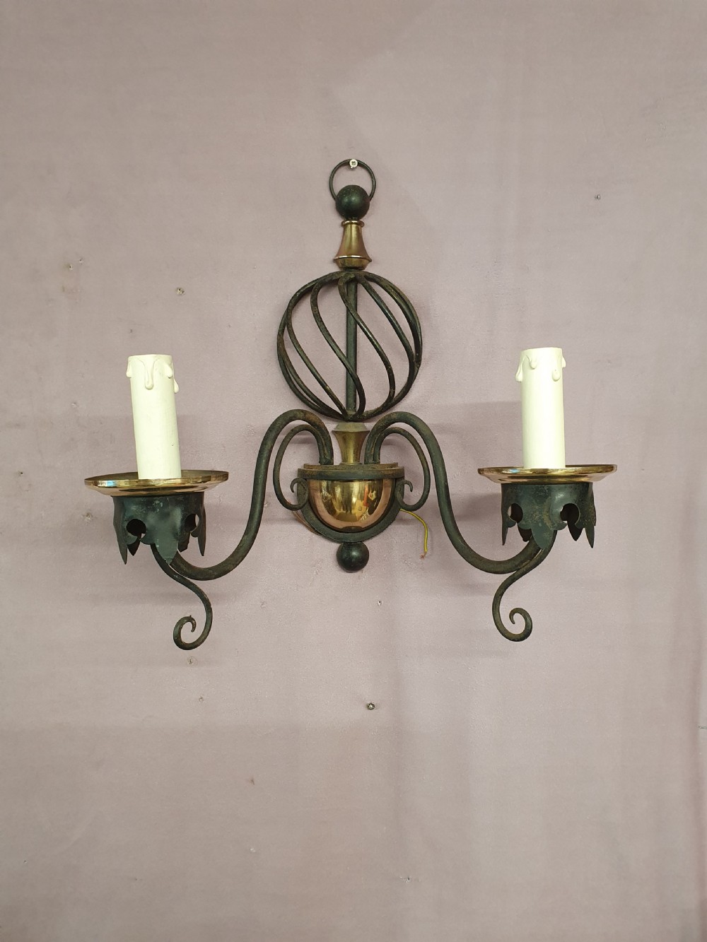 A trio of early twentieth-century dark steel twin-arm wall sconces featuring openwork twisted central cages, scrolled arms, and polished brass accents. View IX