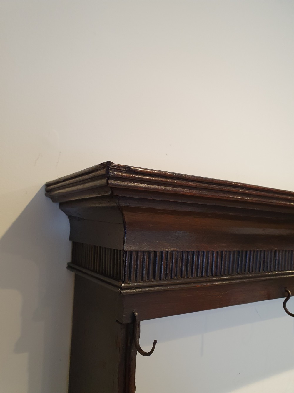 Dark oak early eighteenth-century dresser rack featuring a projecting moulded cornice, three open shelves, and small metal cup hooks. View III