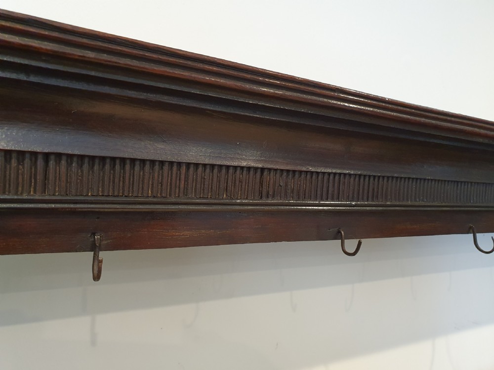 Dark oak early eighteenth-century dresser rack featuring a projecting moulded cornice, three open shelves, and small metal cup hooks. View V