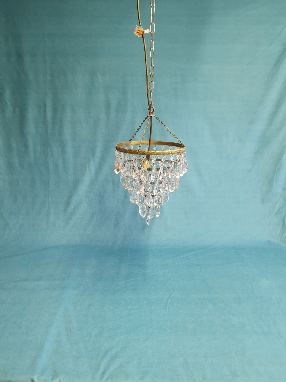 An early 20th-century ceiling light featuring an embossed brass ring with cascading tiers of teardrop-shaped glass crystals hanging from three brass chains. View II