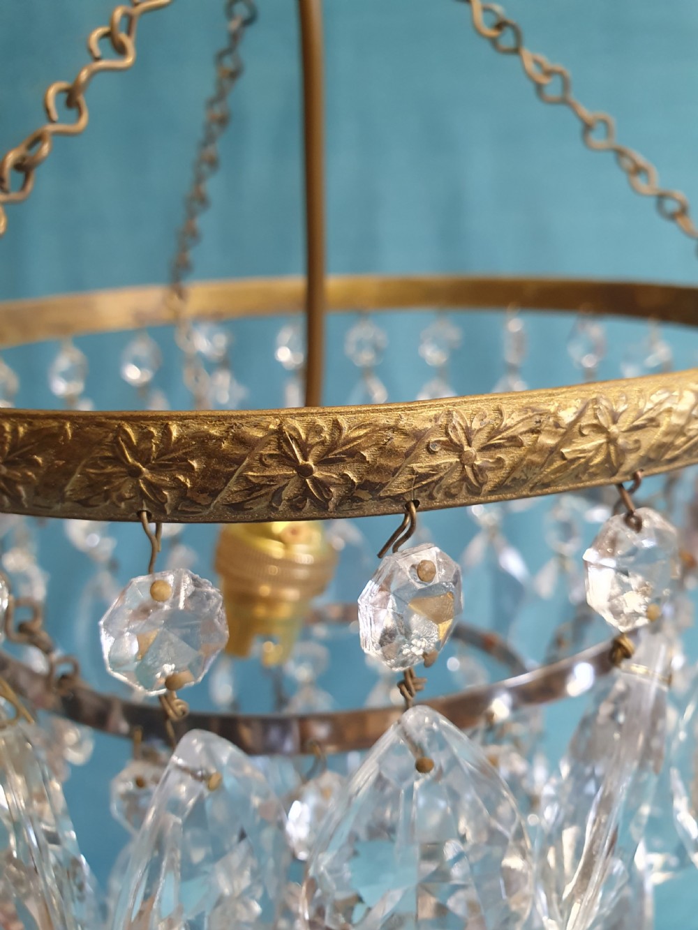 An early 20th-century ceiling light featuring an embossed brass ring with cascading tiers of teardrop-shaped glass crystals hanging from three brass chains. View III