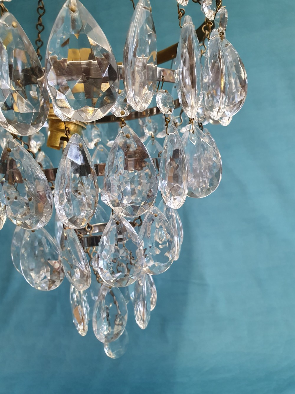 An early 20th-century ceiling light featuring an embossed brass ring with cascading tiers of teardrop-shaped glass crystals hanging from three brass chains. View VI