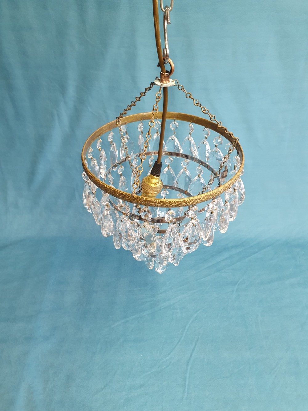 An early 20th-century ceiling light featuring an embossed brass ring with cascading tiers of teardrop-shaped glass crystals hanging from three brass chains. View VIII