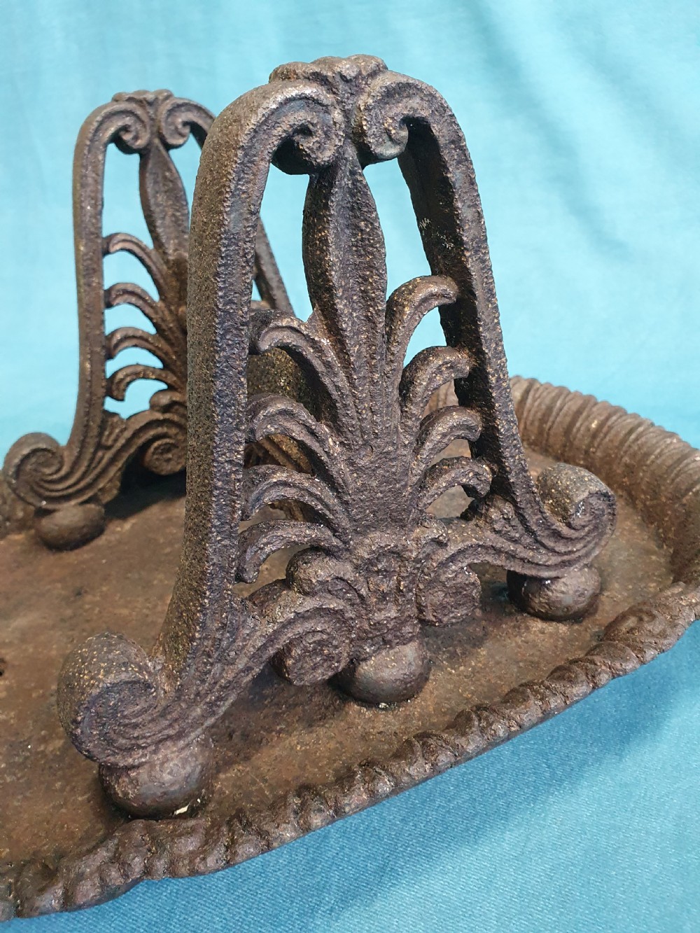 A 19th-century cast iron boot scraper featuring a dished oval tray base and two ornate scrollwork side supports holding a central scraping blade. View III