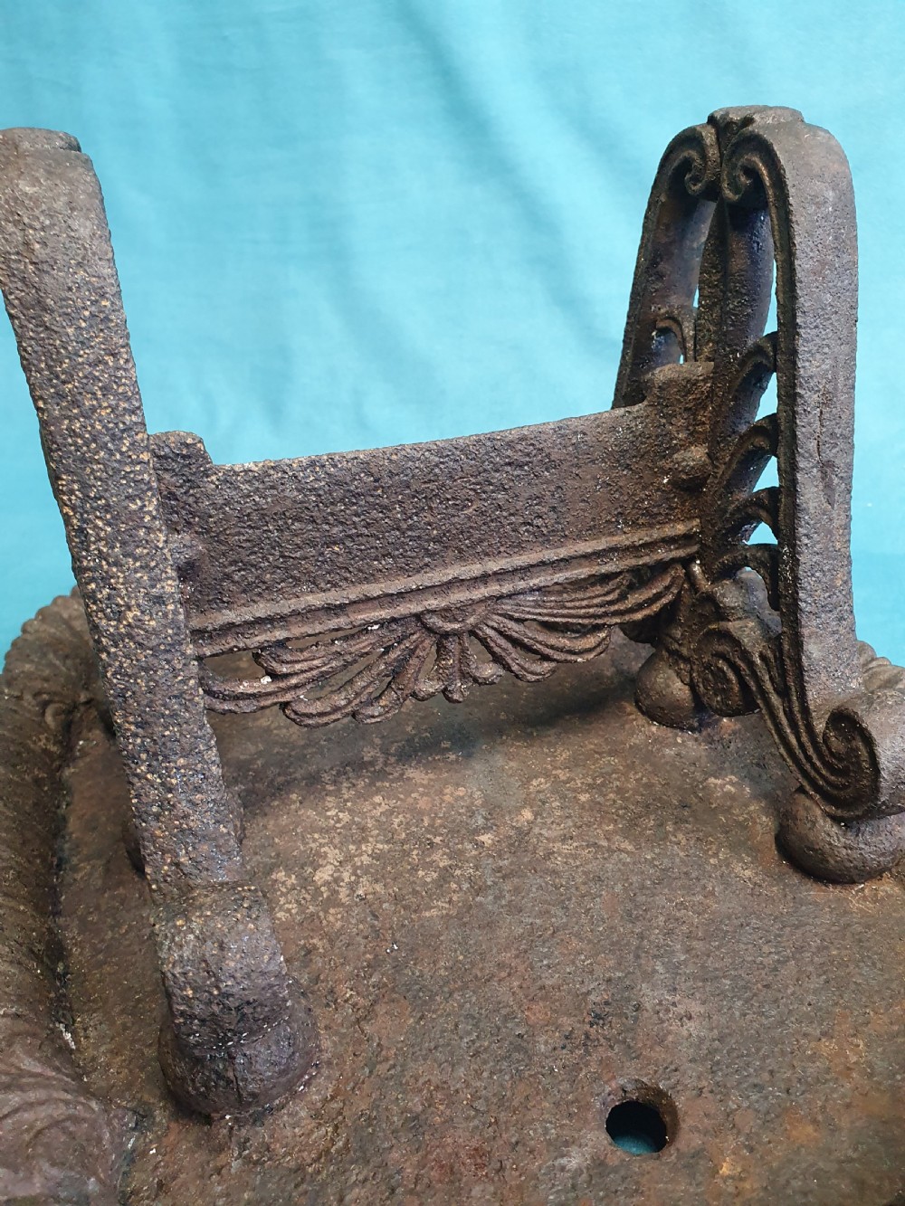 A 19th-century cast iron boot scraper featuring a dished oval tray base and two ornate scrollwork side supports holding a central scraping blade. View IV