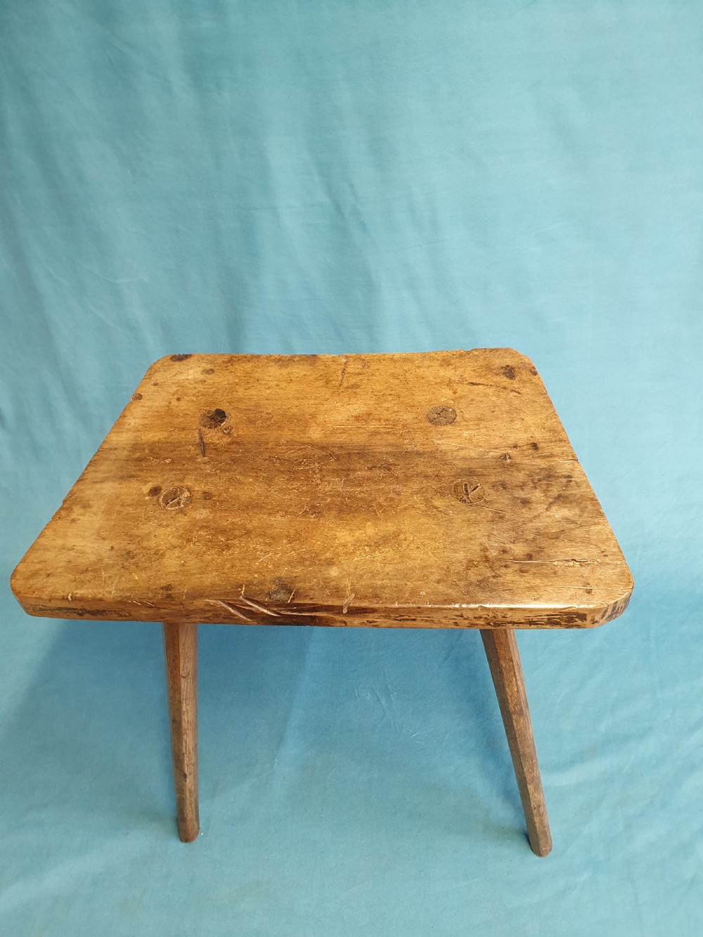 A late 19th-century walnut stick stool featuring a rectangular thick wooden seat raised on four round splayed legs. View VI