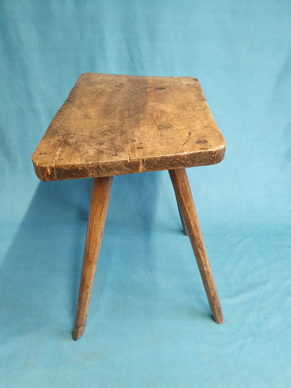 A late 19th-century walnut stick stool featuring a rectangular thick wooden seat raised on four round splayed legs. View VII