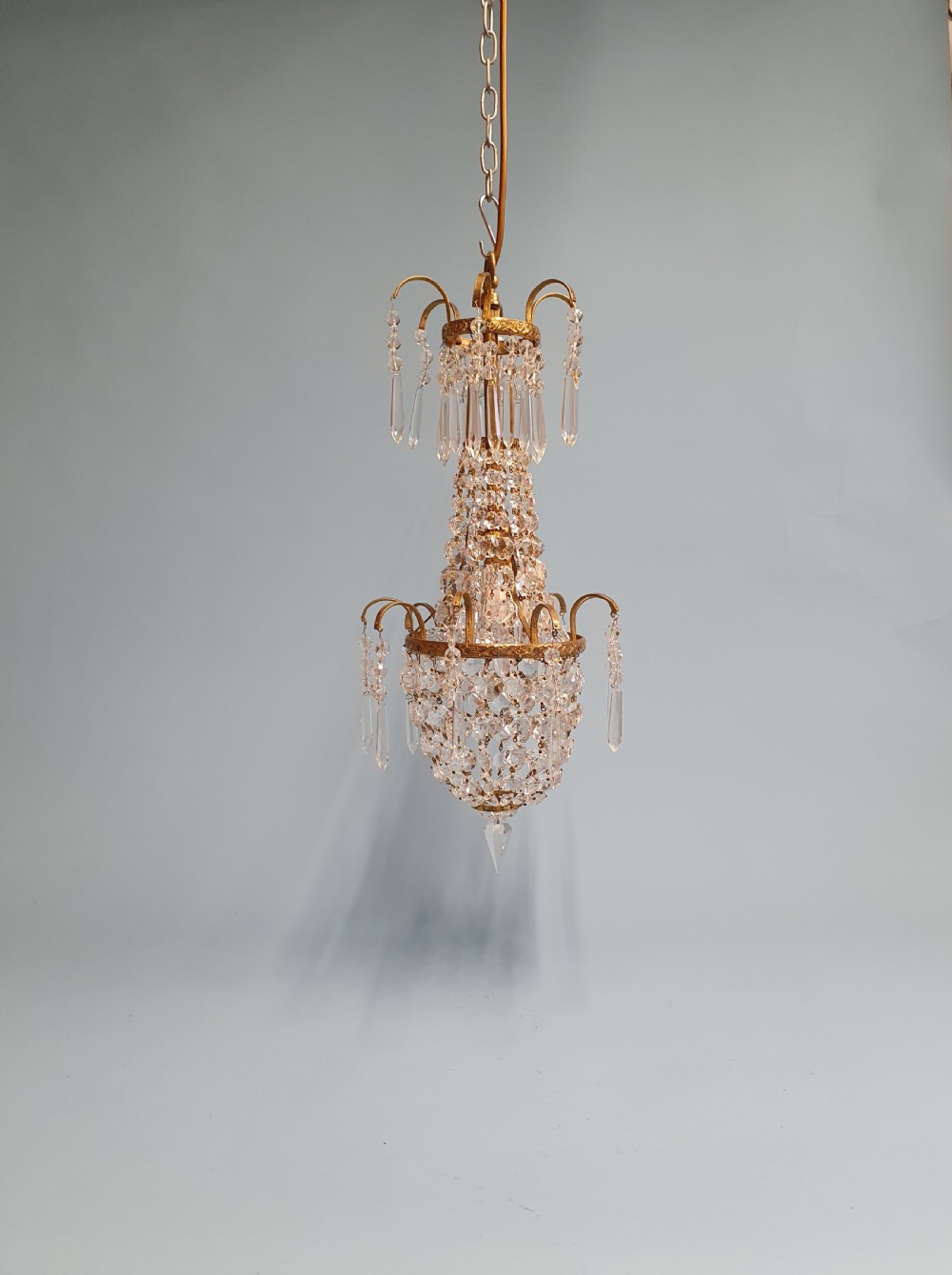 An early 20th-century small swag chandelier featuring a gilt brass frame draped with crystal beads and hanging faceted prisms.