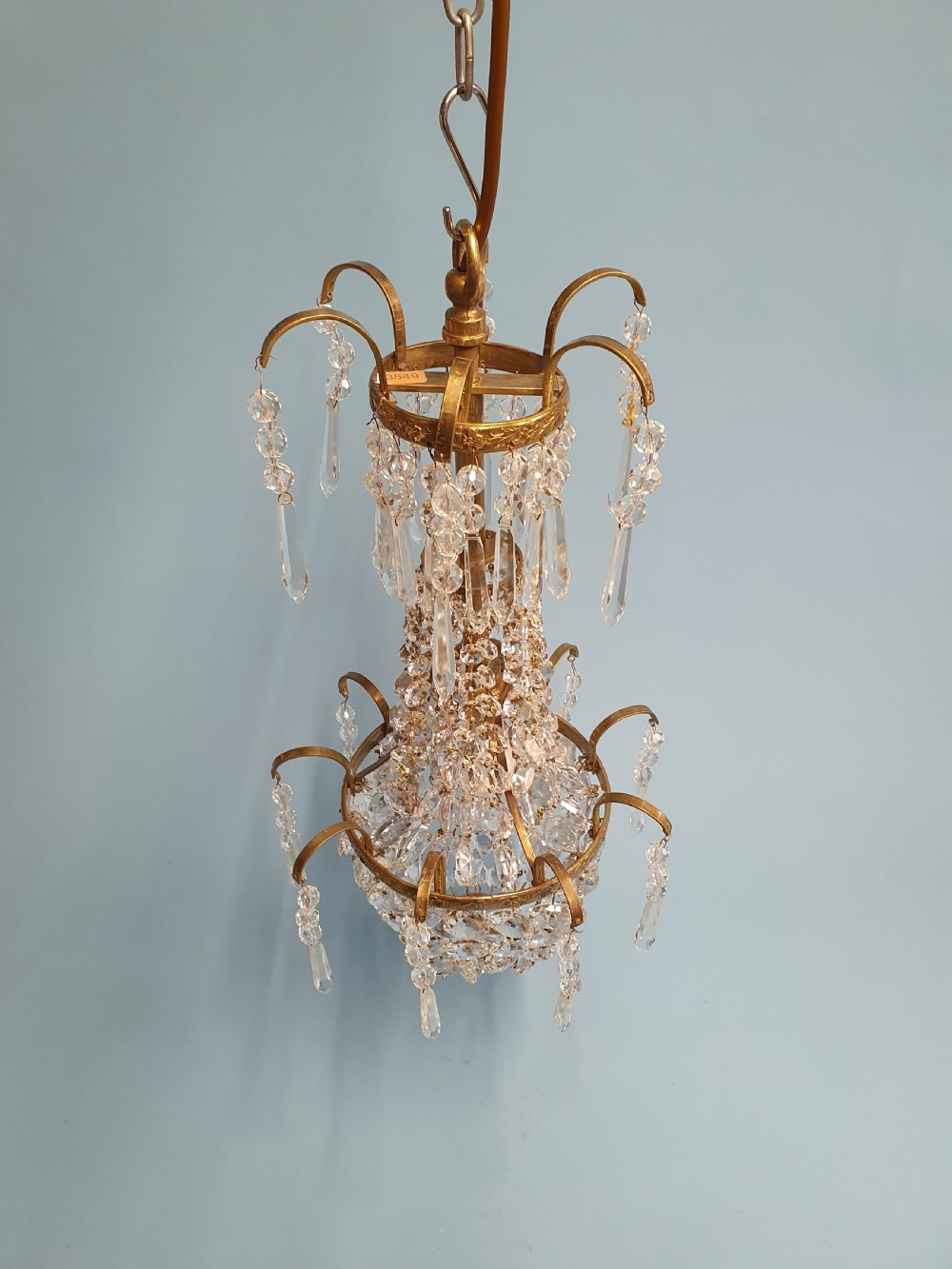 An early 20th-century small swag chandelier featuring a gilt brass frame draped with crystal beads and hanging faceted prisms. View III