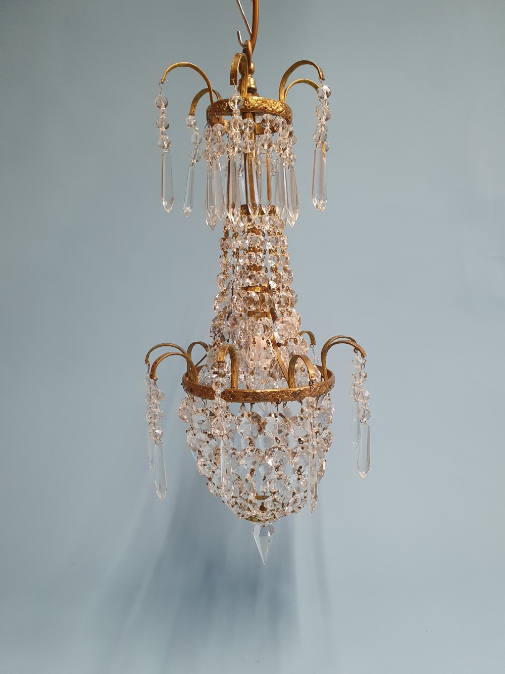 An early 20th-century small swag chandelier featuring a gilt brass frame draped with crystal beads and hanging faceted prisms. View V