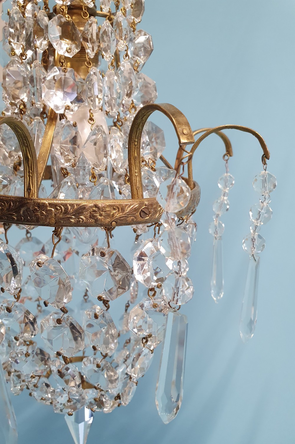 An early 20th-century small swag chandelier featuring a gilt brass frame draped with crystal beads and hanging faceted prisms. View VI
