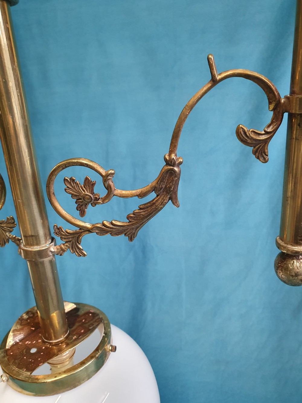 An early 20th-century Gothic Revival linear brass chandelier featuring a horizontal bar structure with ornate scrollwork brackets and two suspended white opaline glass globes. View VI
