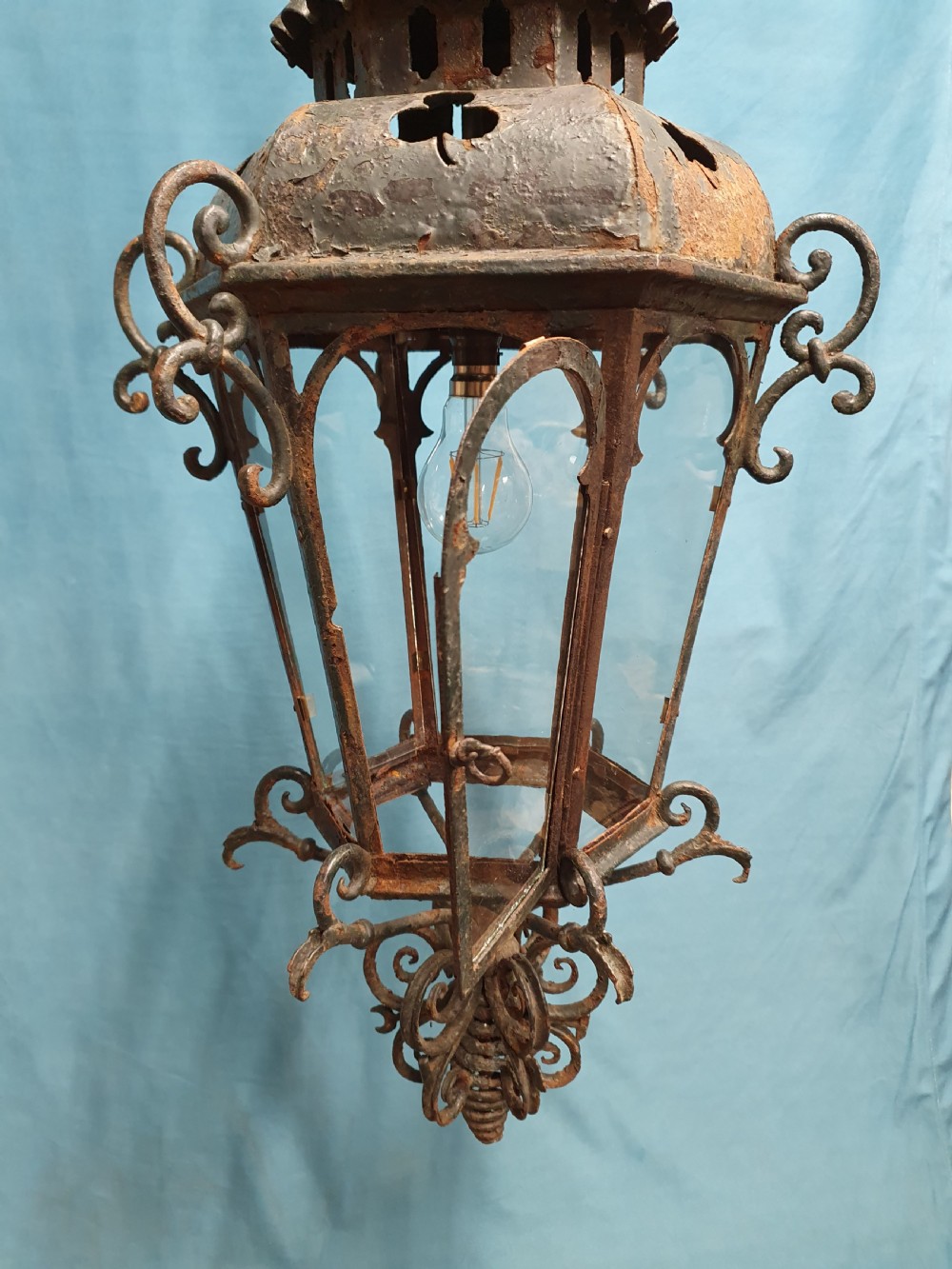 A late 19th-century wrought iron hanging lantern featuring decorative scrollwork, shamrock cutouts along the top canopy, and clear glass side panels. View IV