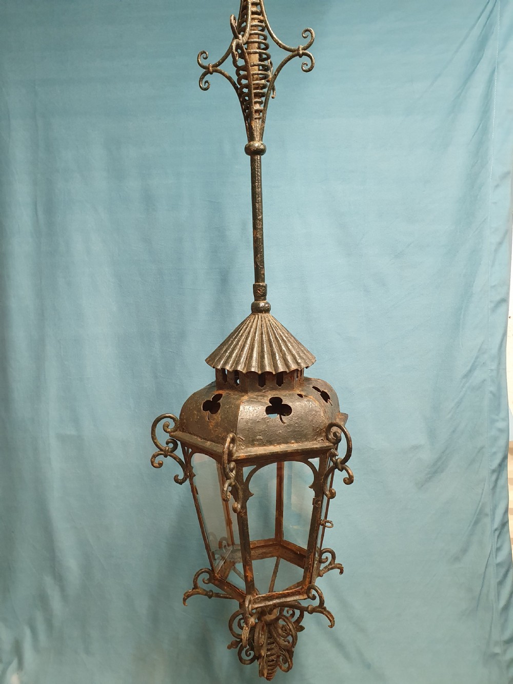 A late 19th-century wrought iron hanging lantern featuring decorative scrollwork, shamrock cutouts along the top canopy, and clear glass side panels. View V