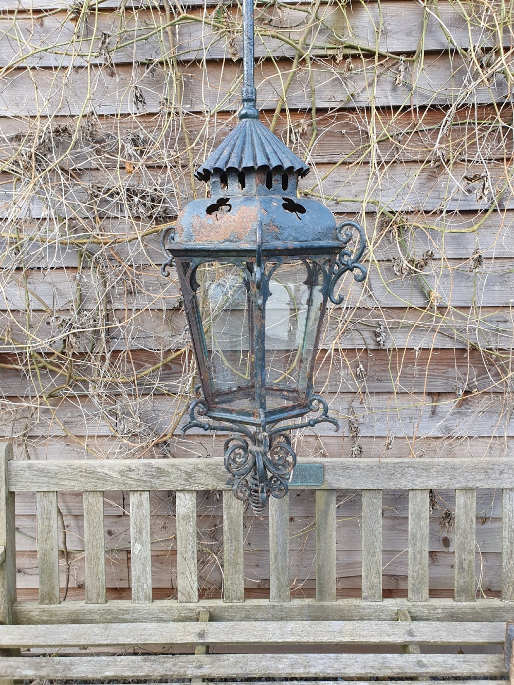 A late 19th-century wrought iron hanging lantern featuring decorative scrollwork, shamrock cutouts along the top canopy, and clear glass side panels. View VII