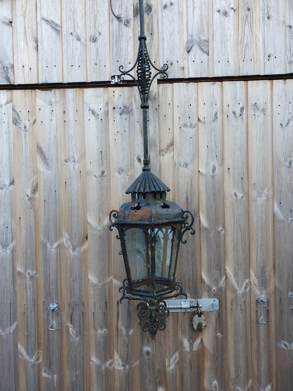 A late 19th-century wrought iron hanging lantern featuring decorative scrollwork, shamrock cutouts along the top canopy, and clear glass side panels. View X