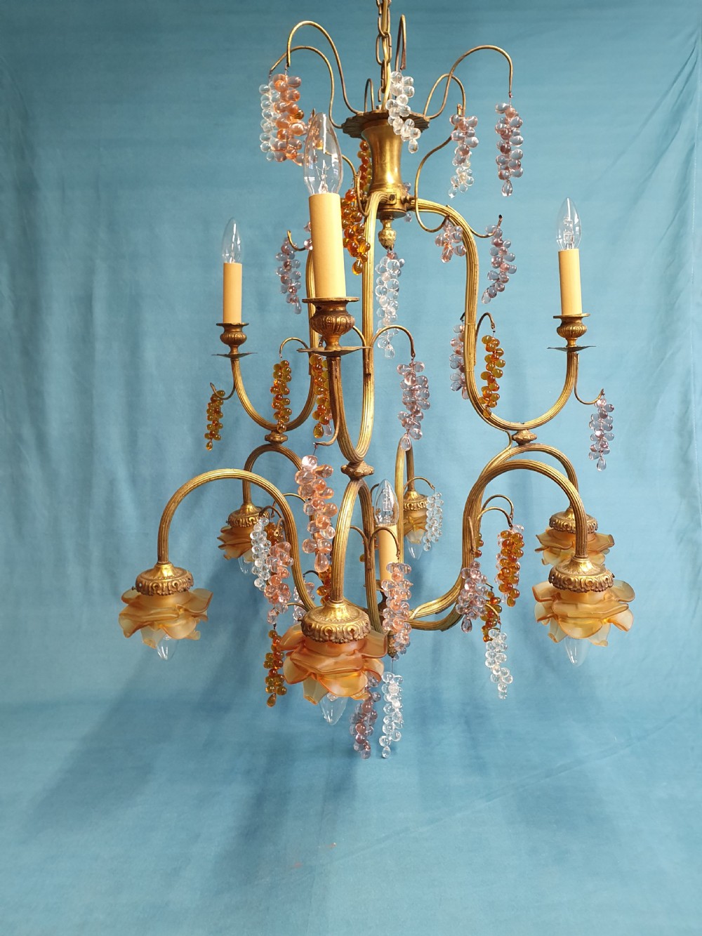 A French brass chandelier adorned with multi-coloured glass grape clusters, scrollwork arms, floral glass cups, and white lampshades. View III