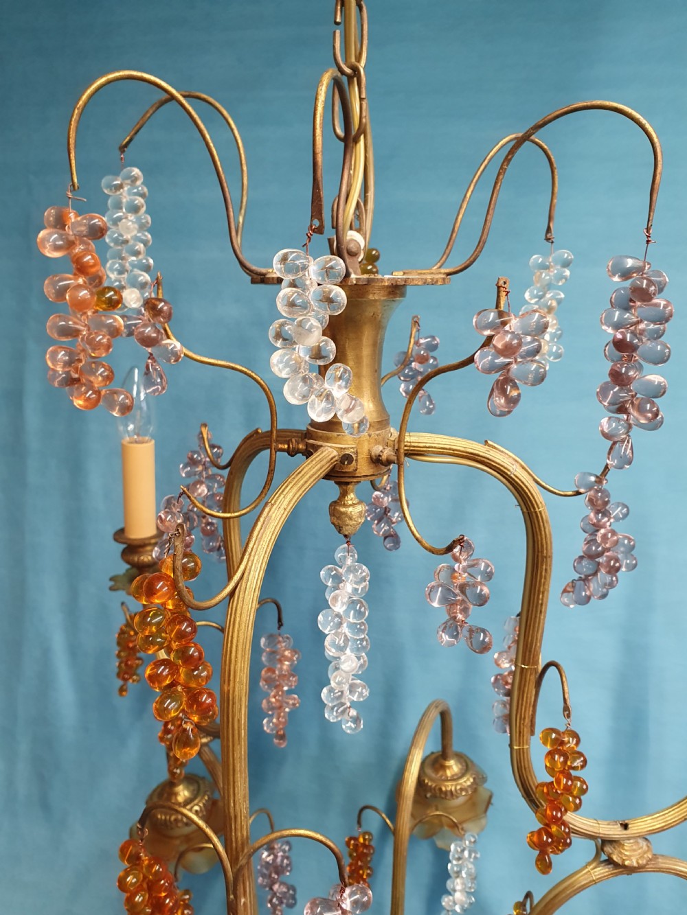 A French brass chandelier adorned with multi-coloured glass grape clusters, scrollwork arms, floral glass cups, and white lampshades. View VI
