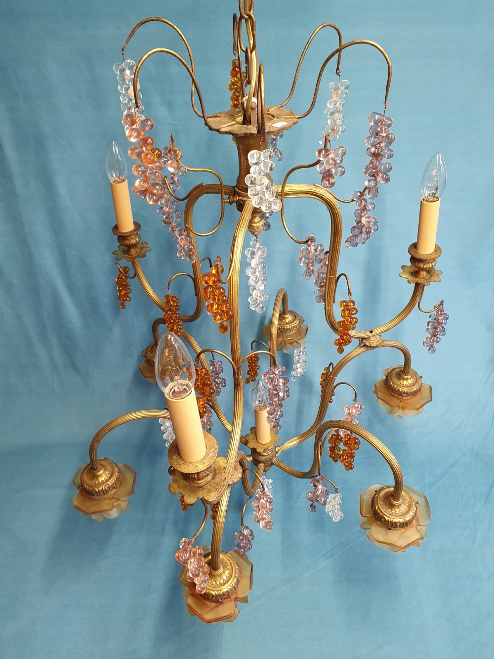 A French brass chandelier adorned with multi-coloured glass grape clusters, scrollwork arms, floral glass cups, and white lampshades. View VII